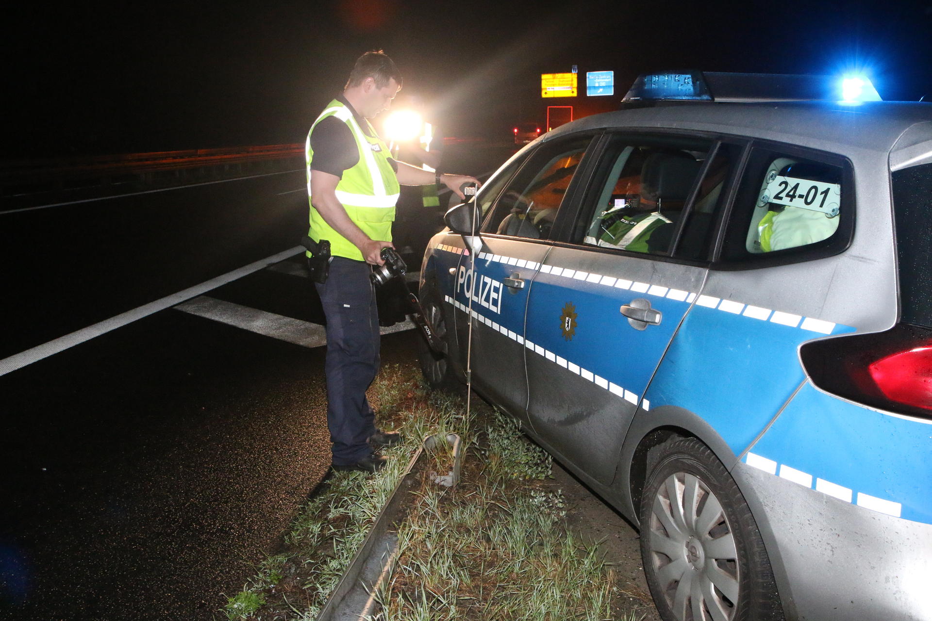 Ein Polizist dokumentiert die Schäden an einem der eingesetzten Streifenwagen. 