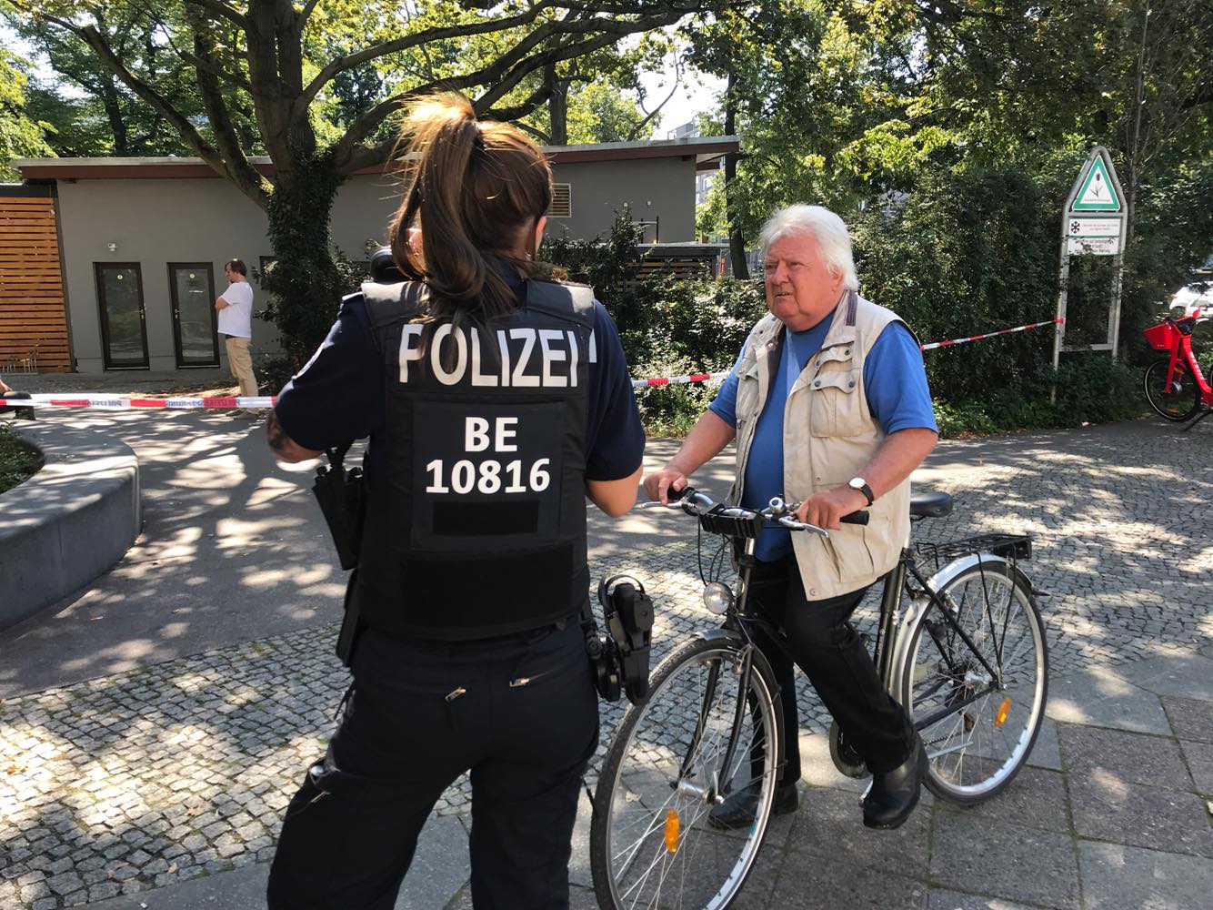 Eine Polizistin spricht in Tatortnähe mit einem Passanten. 