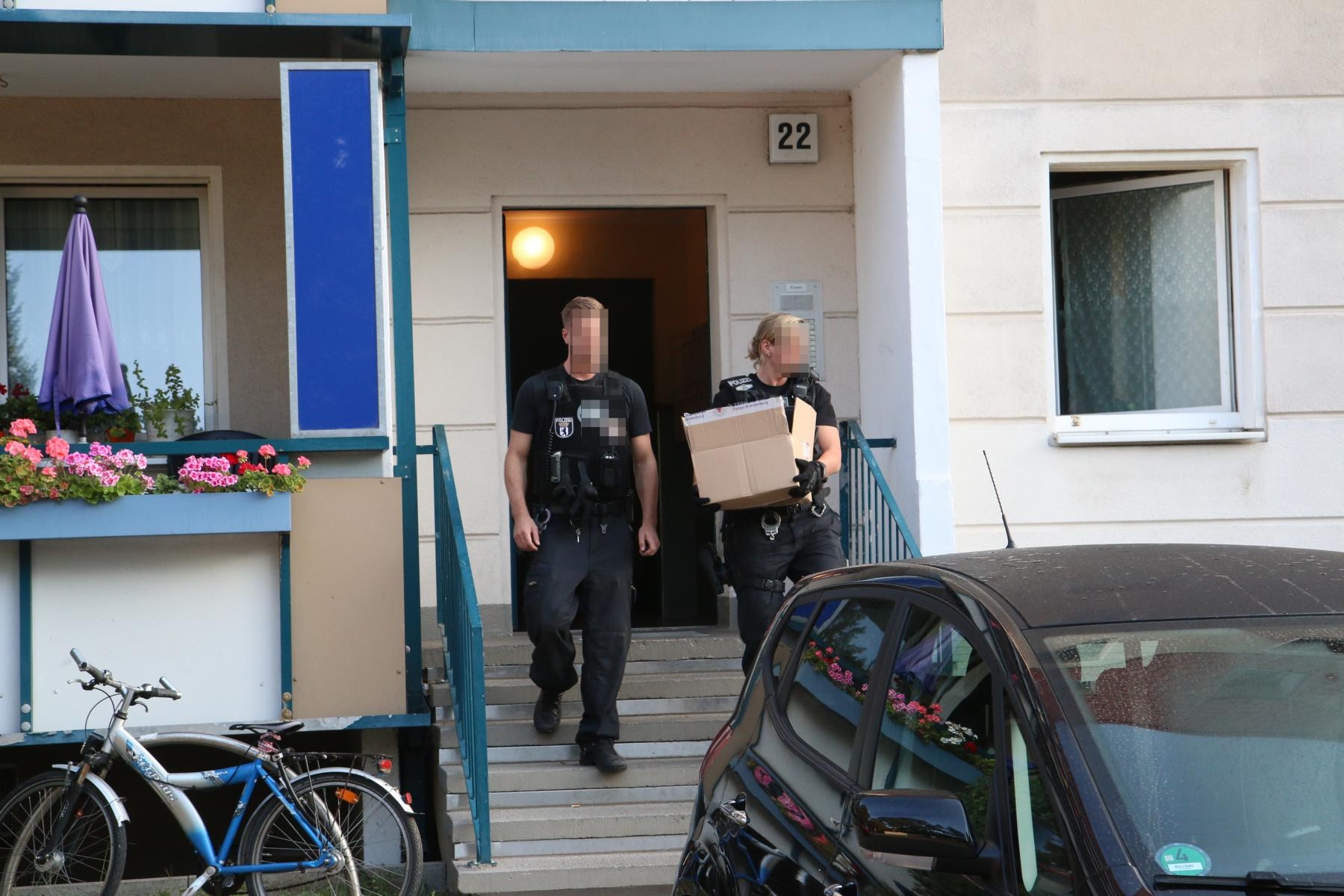 Einsatzkräfte der Polizei tragen mögliche Beweismittel aus dem Haus in Köpenick. 