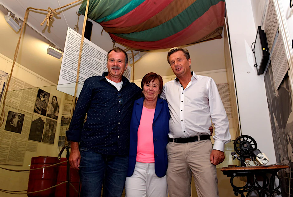 Doris Strelzyk (72) steht mit ihren Söhnen Frank (56, links) und Andreas (51) vor der Gondel im Mauermuseum. 