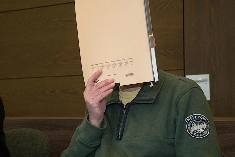 Der Angeklagte Bernd U. verbirgt im Gerichtssaal sein Gesicht hinter einer Aktenmappe.