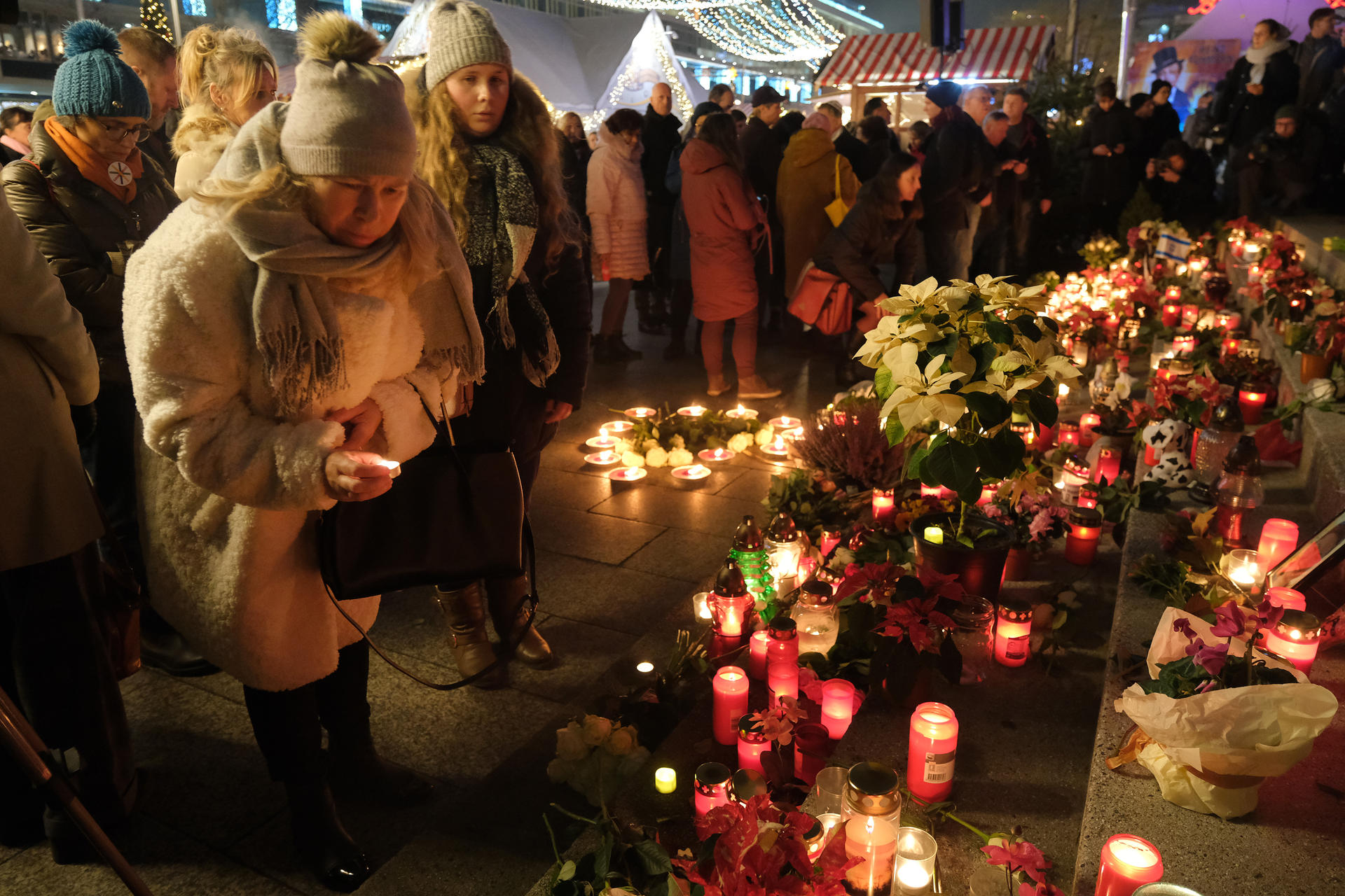Menschen versammeln sich an den Stufen mit den Namen der zwölf Verstorbenen, die zur Kirche hinaufführen.