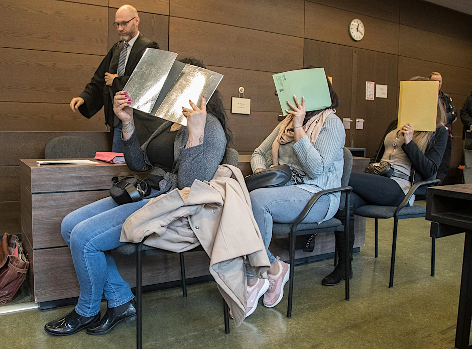 Die drei Angeklagten verdecken ihre Gesichter. 