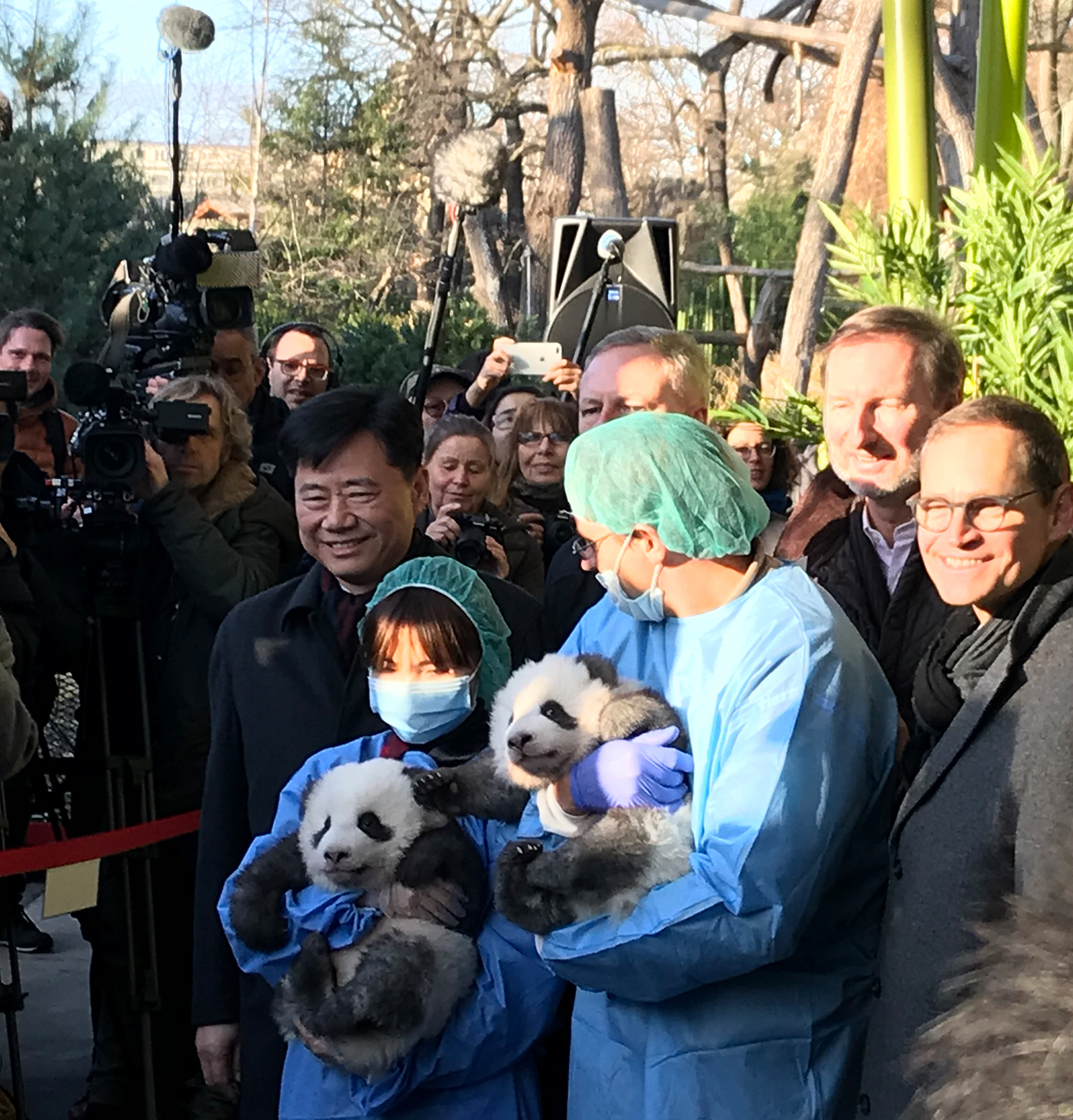 Die Zwillinge in den Armen ihrer Pfleger. flankiert vom Regierenden Bürgermeister Michael Müller, Zoo-Chef Andreas Knieriem und dem chinesischen Botschafter in Deutschland Wu Ken (v. r. n. l.)