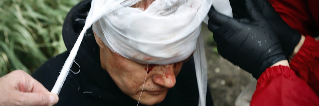 Demonstranten verbinden den blutig geschlagenen Kopf eines Protest-Teilnehmers.
