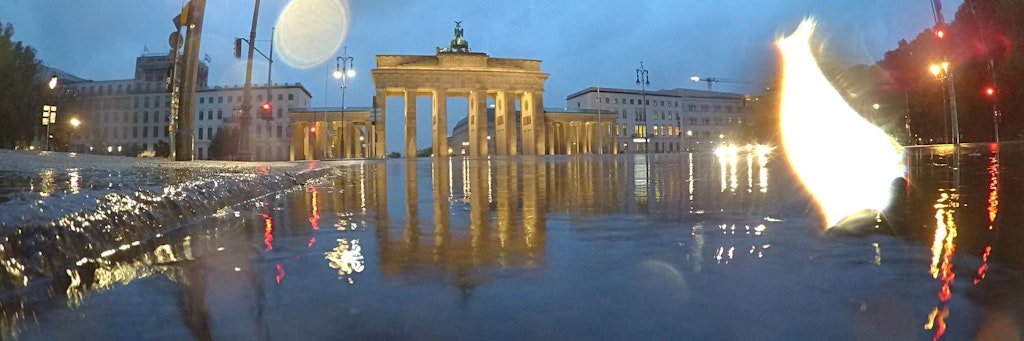 Der Regen hat eine Pfütze vor dem Brandenburger Tor gebildet, doch die Böden bleiben knochentrocken.
