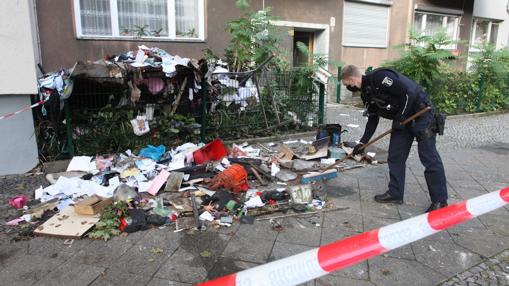 Ein Polizist kehrt vor dem Haus in der Steinmetzstraße die zum Teil verbrannten Sachen der Familie zusammen. 