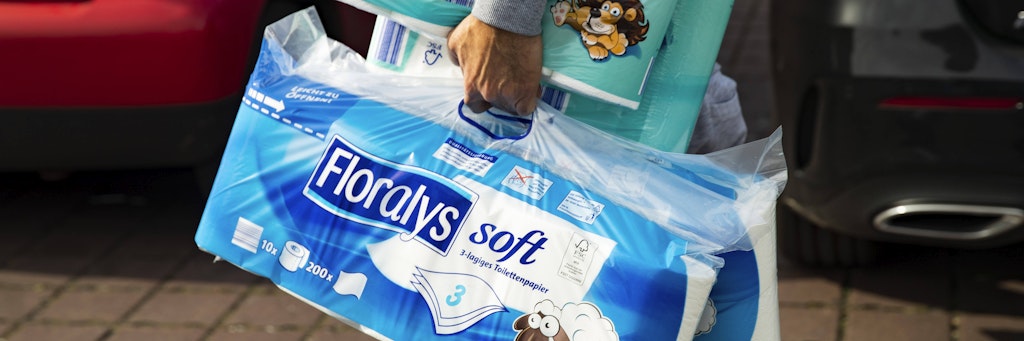 Ein Mann trägt mehrere Packungen Toilettenpapier (Symbolbild).
