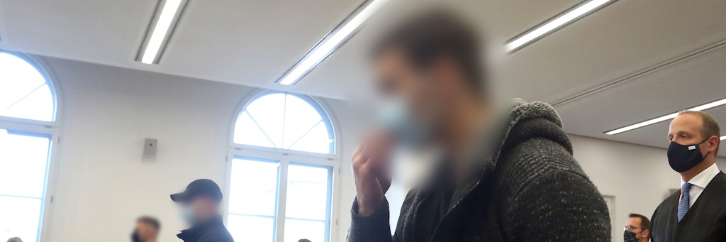 Der Hauptangeklagte (r.) steht neben seinen Mittäter im Gerichtssaal.