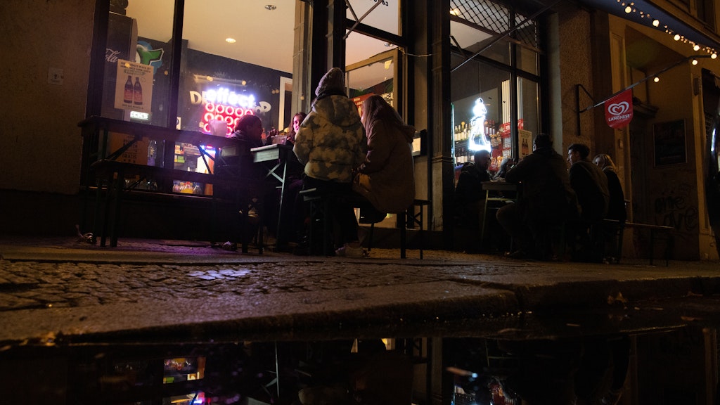 Menschen sitzen vor Beginn der Sperrstunde vor einem Spätkauf an der Oranienstraße. 