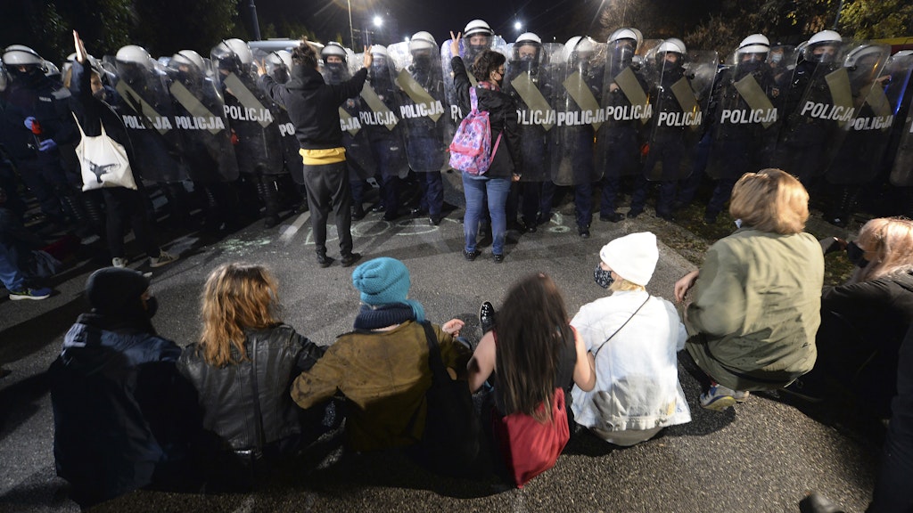 Polizisten bewachen das Haus des polnischen Vize-Ministerpräsidenten Kaczynski, währernd Demonstranten gegen die Entscheidung des Verfassungsgerichts protestieren.