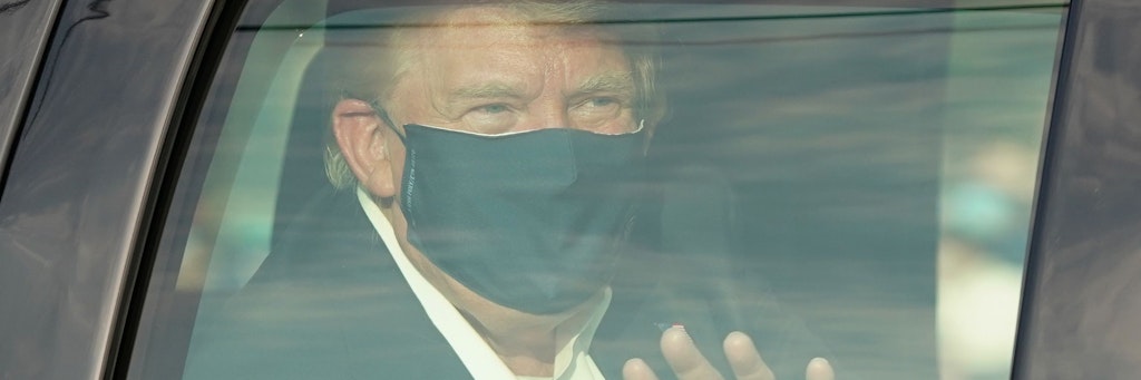 Präsident Donald Trump lässt sich von Bodyguards herumkutschieren, winkt seinen wartenden Fans aus dem Auto zu.