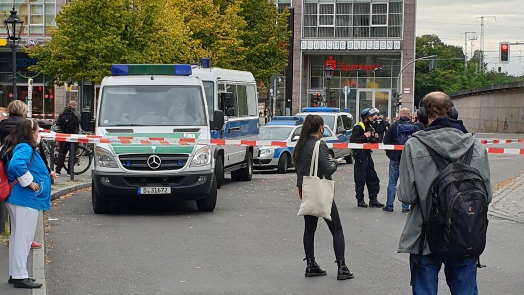 Passanten stehen vor der Absperrung. 