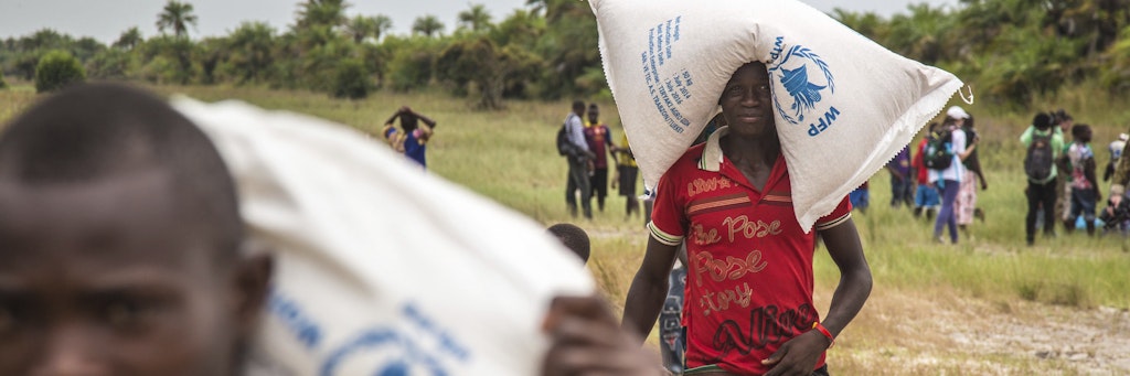 Junge Männer in Sierra Leone schleppen Getreidesäcke - Hungerhilfe des Welternährungsprogramms, abgeworfen von einem Hubschrauber. 