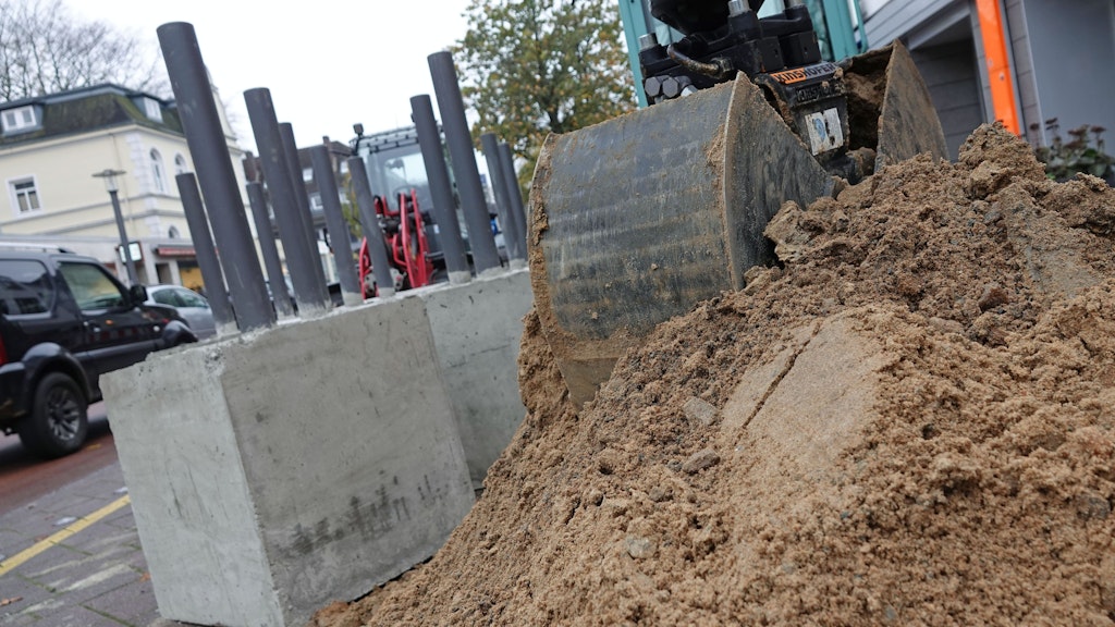 Vollstahlpoller stehen neben einem Sandhaufen an der Hamburger Waitzstraße. In der von zahlreichen Schaufenster-Unfällen geplagten Straße sollen sie die Geschäfte schützen.
