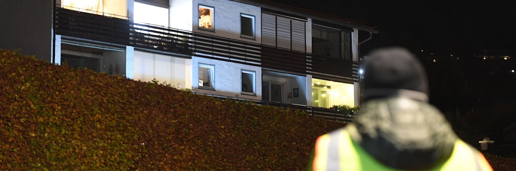 Ein Mitarbeiter der Polizei steht vor dem Tatort. Ein Mann hat im oberbayerischen Tegernsee seine Ehefrau als Geisel genommen und sie getötet. 
