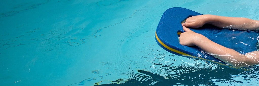 Ein Kind lernt mit einem Gleitbrett das Schwimmen. Doch wegen Corona finden viele Kurse nicht statt.