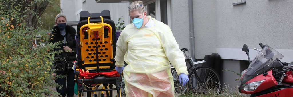 Einsatzkräfte mit Masken, Handschuhen und Umhängen