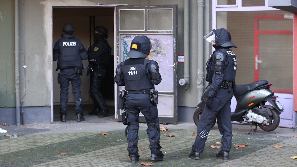 Beamte einer Einsatzhundertschaft bewachen den Eingang des Wohnhauses, in dem Angehörige des Remmo-Clans festgenommen wurden. 