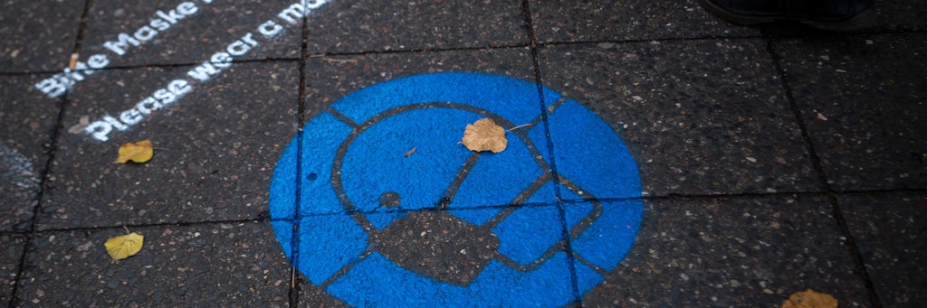 Auf der Bölschestraße, einer großen Einkaufsstraße, wird mit Hinweisen auf dem Pflaster auf die Maskenpflicht aufmerksam gemacht. 