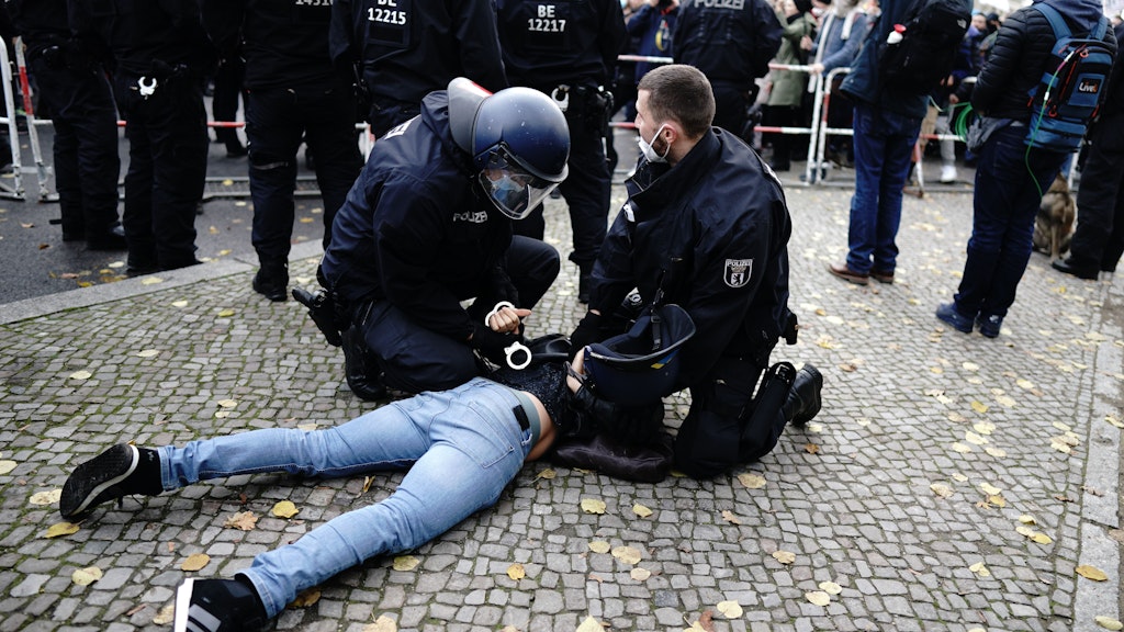 Einsatzkräfte der Polizei halten einen am Boden liegenden Teilnehmer einer Demonstration gegen die Corona-Einschränkungen der Bundesregierung vor dem Brandenburger Tor fest.