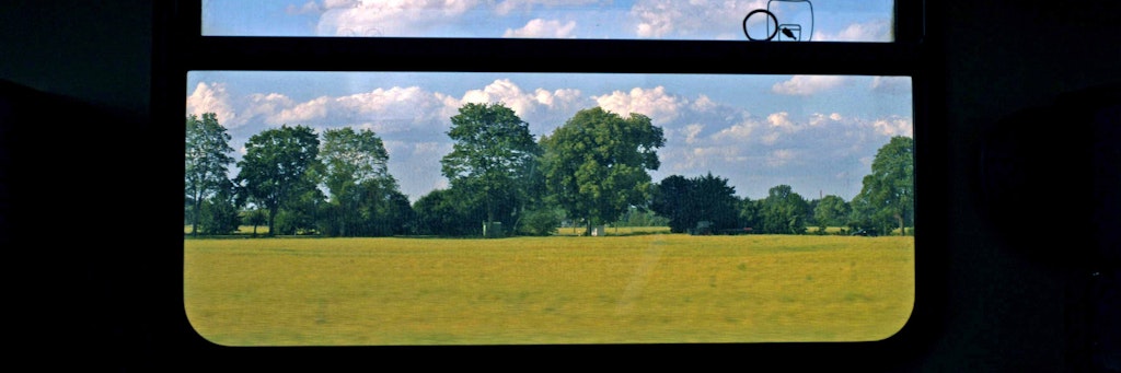 Idyllische Landschaft vor einem Zugfenster.