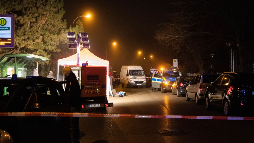 Polizeibeamte arbeiten am abgesperrten Tatort in der Nähe einer Haltestelle.