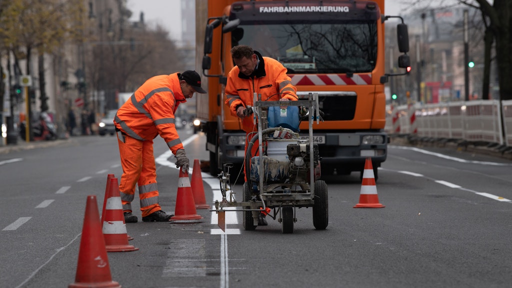 Arbeiter zeichnen neue Fahrspuren auf der Straße Unter den Linden. Nach dem Abbau der Baustelle für die neue U-Bahnlinie U5 vom Roten Rathaus bis zum Brandenburger Tor führen die Fachleute Markierungsarbeiten durch.