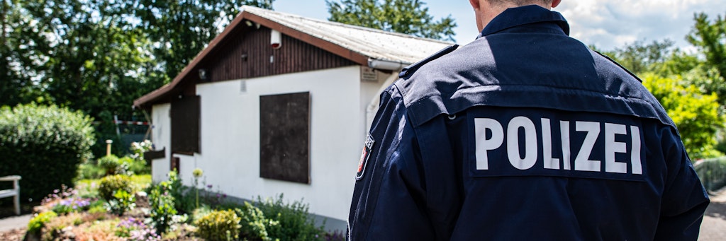 Ein Polizist steht in der Kleingartenanlage von Münster, wo sich der sexuelle Missbrauch abgespielt haben soll.