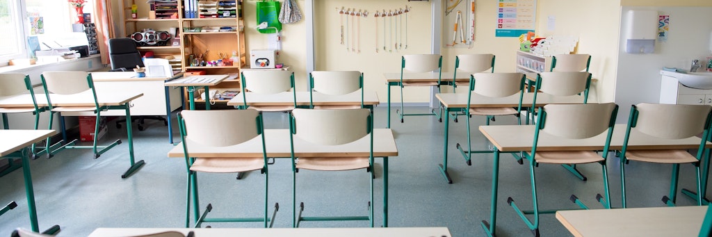 In einem menschenleeren Klassenraum einer Grundschule sind die Stühle hochgestellt. 