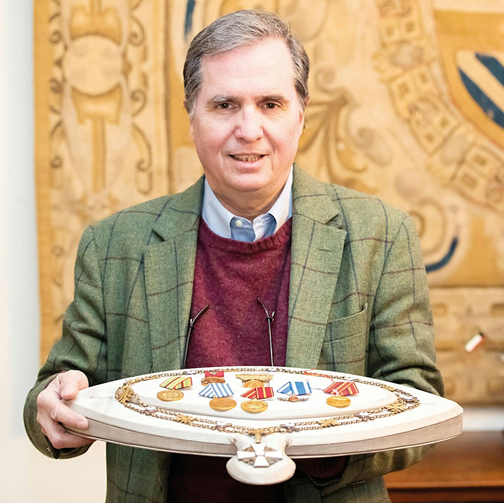 Andreas Thies hält in seinem Aktionshaus eine Platte, auf der eine Ordenskette der weißen Rose von Finnland für Staatsoberhäupter und verschiedene Auszeichnungsmedaillen der DDR aus dem Besitz Erich Honeckers liegen. Daneben steht ein Modell eines Segelschiffes, welches ein Geschenk des Emir von Kuweith an Honecker war.