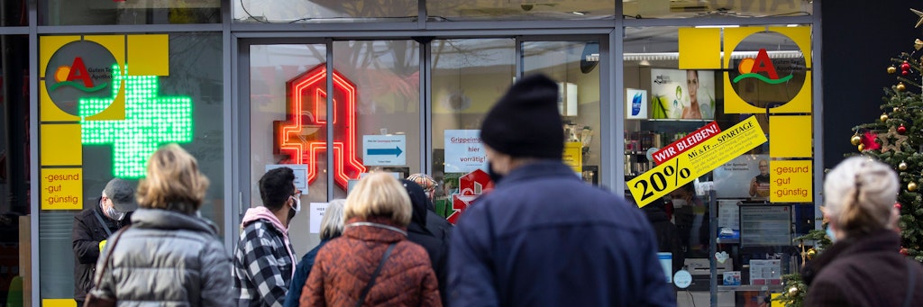 Kunden warten vor einer Apotheke auf kostenlose FFP2-Masken.