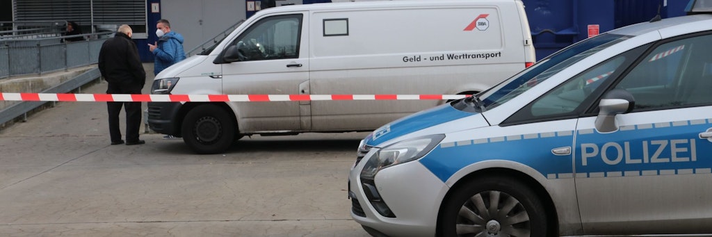 Die Polizei hat den Hinterausgang des Möbelhauses abgesperrt. Zwei Beamte unterhalten sich an dem Geldtransporter. 