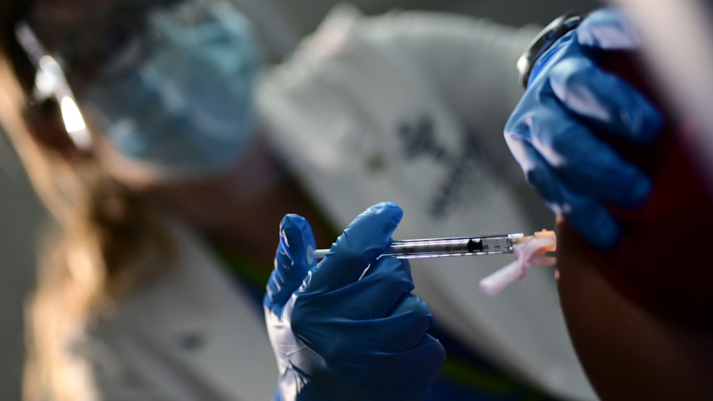 Eine Krankenschwester impft einen Gesundheitsarbeiter mit dem Corona-Wirkstoff von Pfizer-BioNTech. 