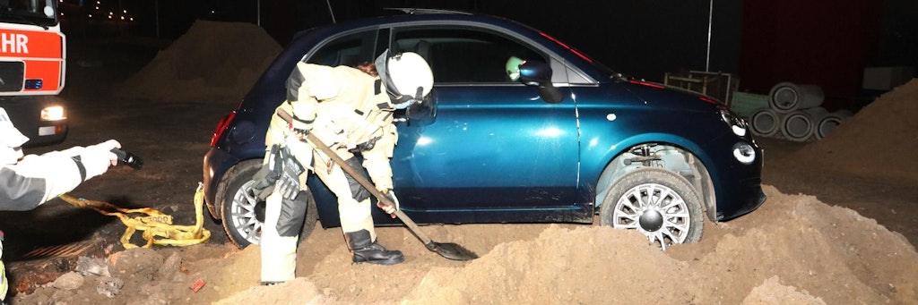 Ein Feuerwehrmann schaufelt in der Nacht zu Samstag den festgefahrenen Fiat 500 frei.