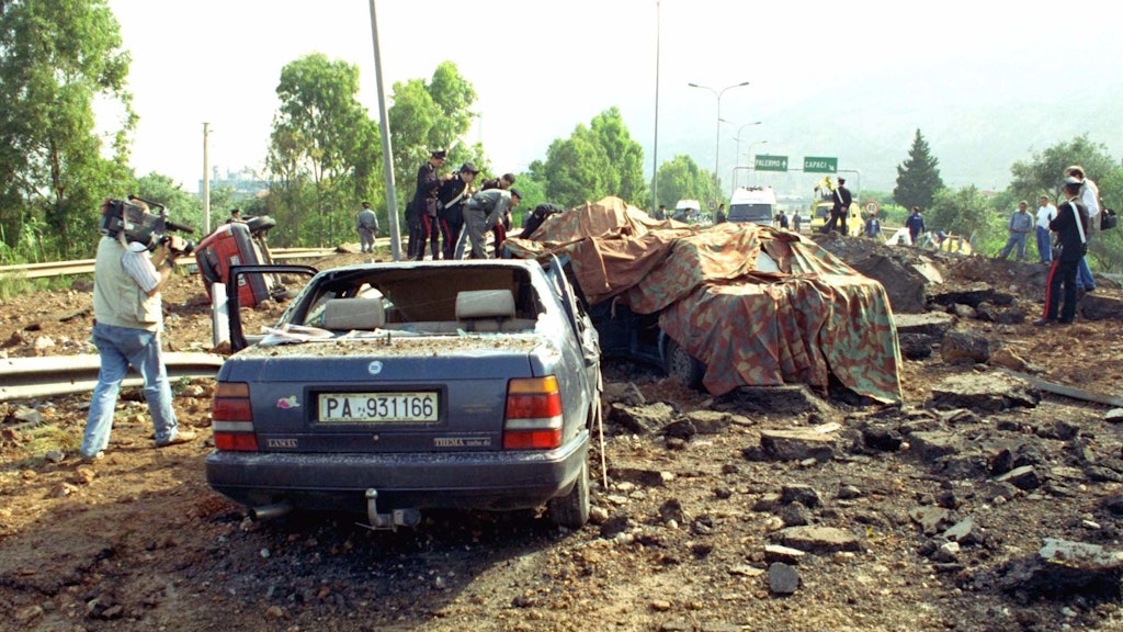 Bei einem Sprengstoffanschlag auf der Autobahn bei Palermo wurden der Ermittlungsrichter Giovanni Falcone, seine Frau und drei Polizisten getötet. Nur sein Fahrer überlebte schwer verletzt. Die sizilianische Mafia „Cosa Nostra“ wollte sicher gehen, setzte eine halbe Tonne TNT ein.