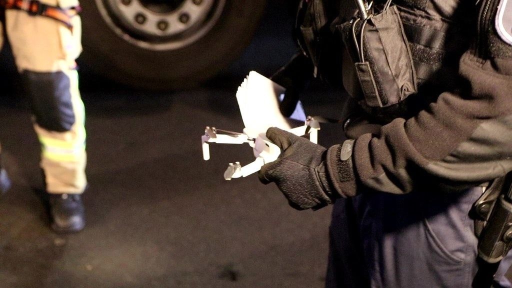 Ein Polizeibeamter hält die Drohne nach erfolgreicher Bergung in der Hand.