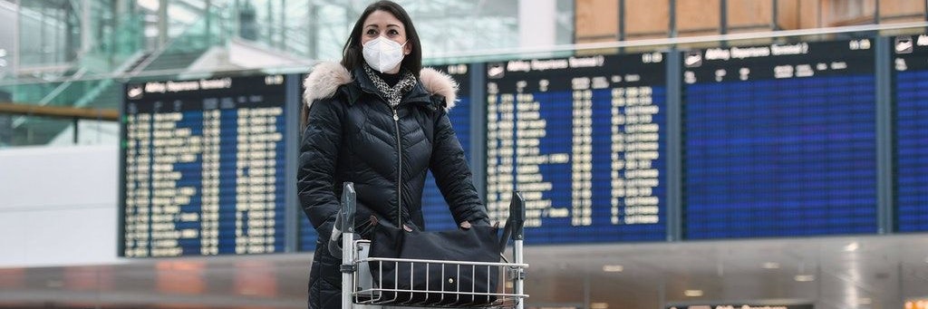 Eine junge Frau steht mit ihrem Gepäck am Flughafen (Symbolbild).