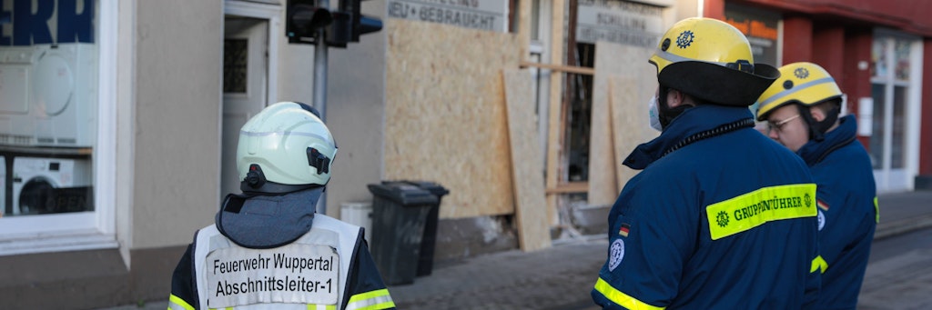 Feuerwehrler begutachten das einsturzgefährdete Haus, nachdem der Kia in das Ladenlokal gekracht war.