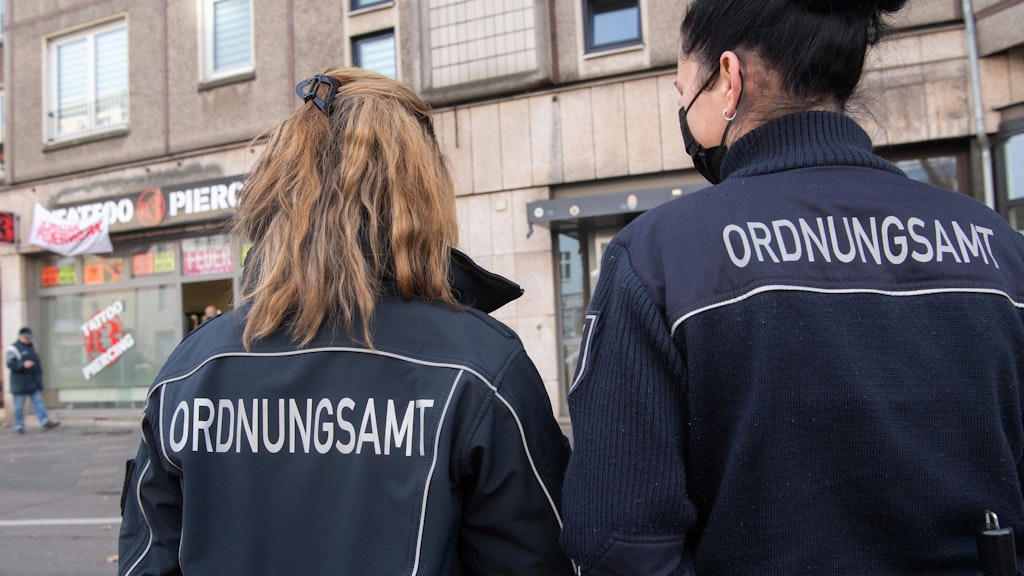 Mitarbeiterinnen des Ordnungsamtes stehen unweit eines Geschäftes an der Frankfurter Allee, das am Montag geschlossen wurde.