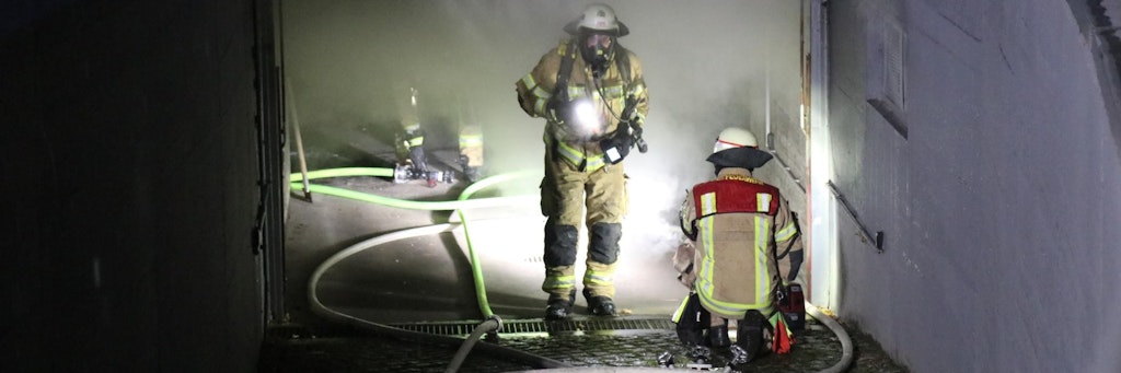 Feuerwehrleute mit Atemschutzmasken löschen den Brand in der Tiefgarage. 