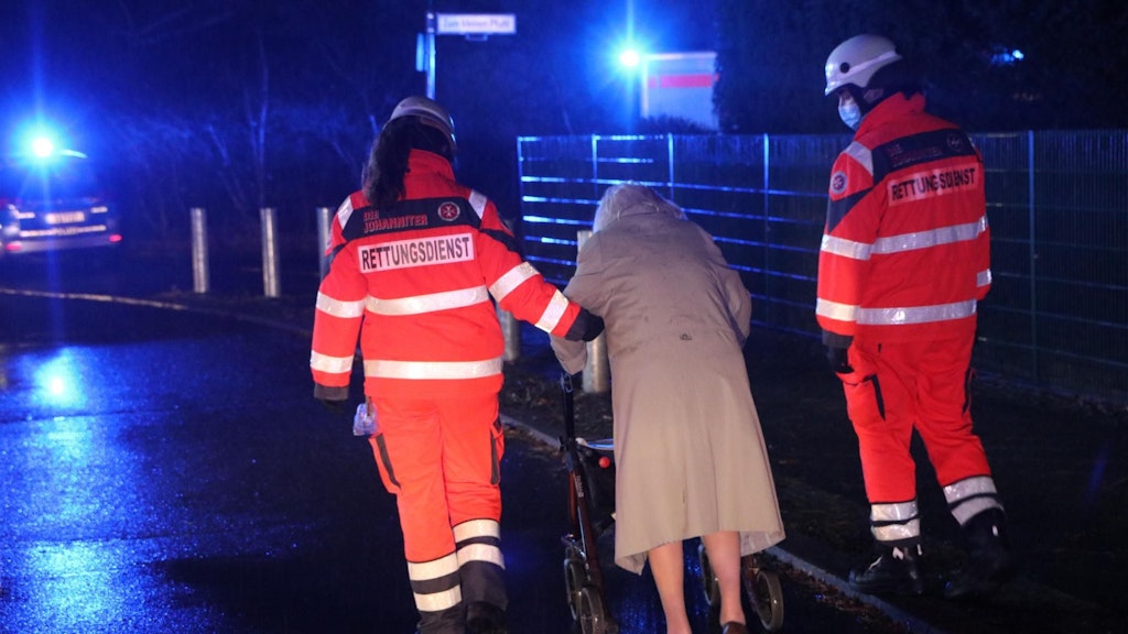 Rettungskräfte bringen eine ältere Dame in Sicherheit. 
