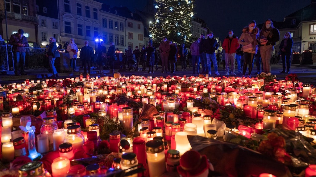 Menschen gedenken vor der Porta Nigra für die Opfer einer Amokfahrt und stellen Kerzen ab.
