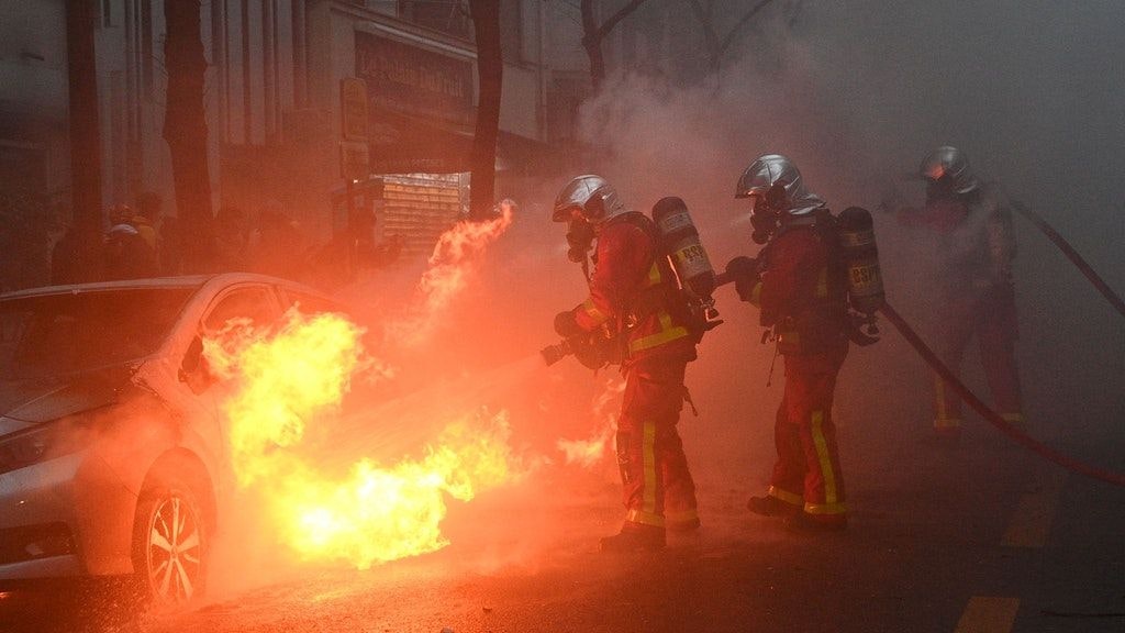 Feuerwehrleute in Paris löschen ein brennendes Fahrzeug.