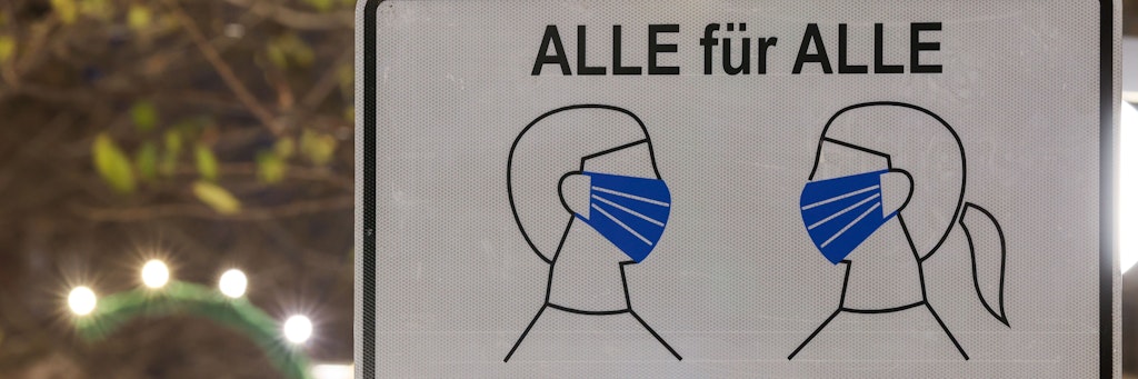 In Leipzig steht ein Schild, das auf eine Maskenpflicht hinweist.