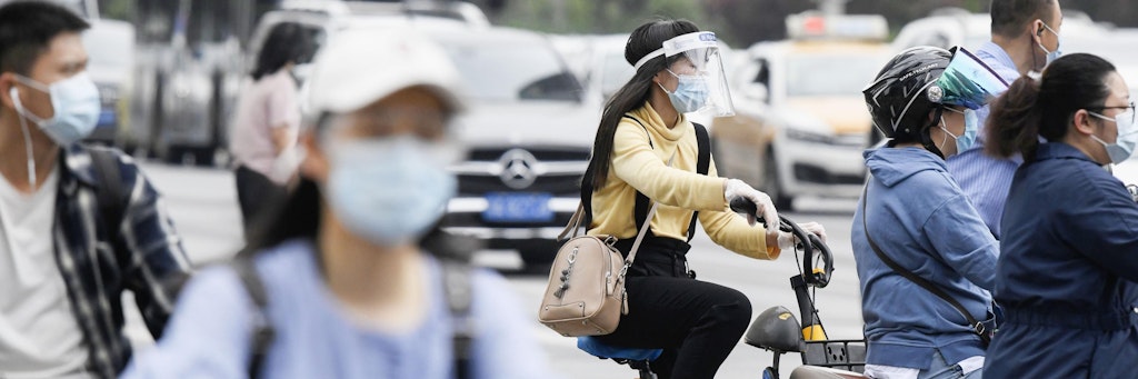 Pendler fahren in Wuhan mit Mund-Nasen-Scutz und Gesichtsschutz auf Motorrädern und Fahrrädern zur Arbeit. Gut ein Jahr nach dem Ausbruch gilt das Coronavirus in China als so gut wie besiegt. 