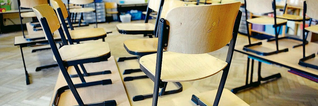 Stühle stehen in einer Schule nach Unterrichtsende auf den Tischen. 