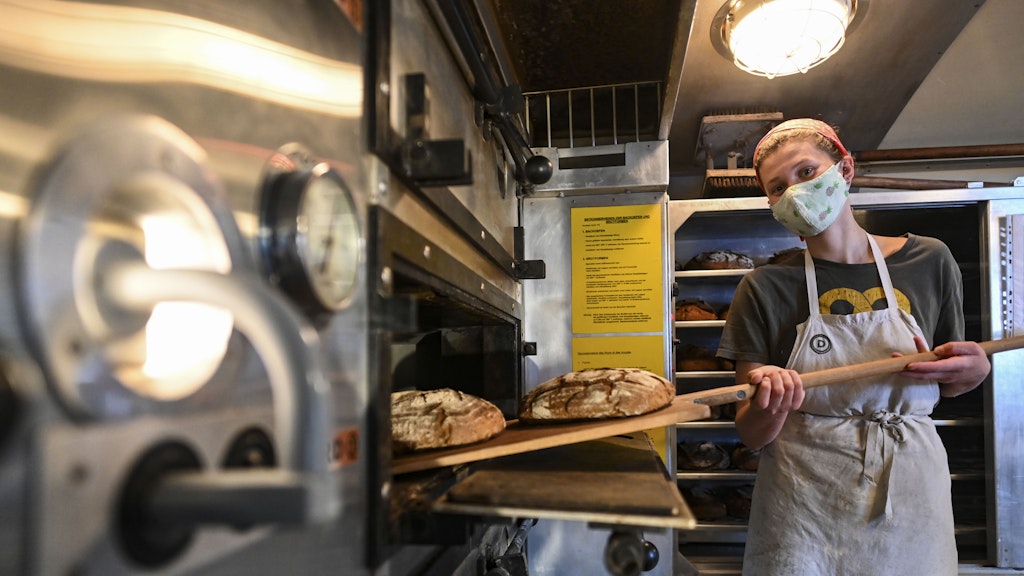 Anna (22) holt das fertige Brot aus dem Ofen. 