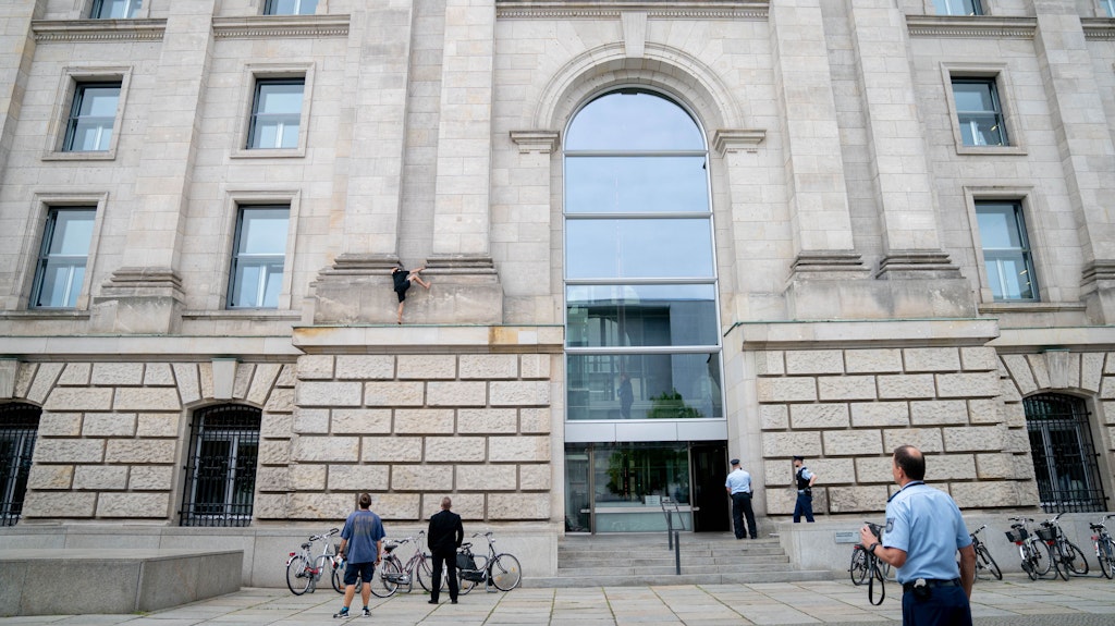Ein Mann klettert die Fassade des Reichtagsgebäudes hinauf. Im Reichstagsgebäude tagte zeitgleich der Bundestag. 