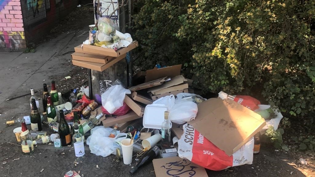 An den Abfallbehältern türmt sich der Müll.<br>